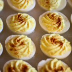Close up image of 2 rows of classic deviled eggs sprinkled with paprika