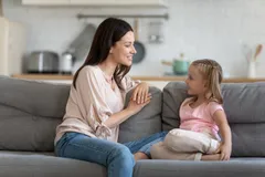 Mother speaking to her strong-willed child while sitting on the couch together